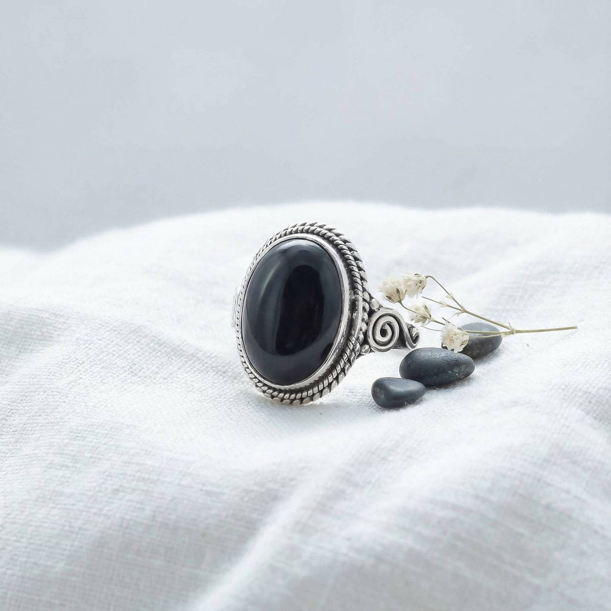 Silberring mit Onyx auf hellem Stoff