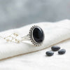 [KI] Silberring mit Onyx auf hellem Stoff