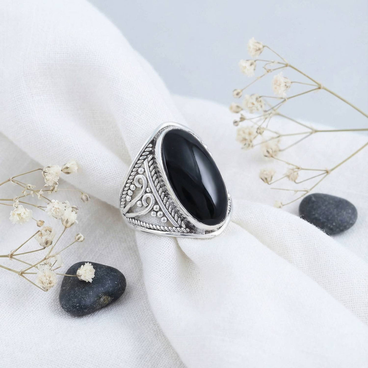 Silberring mit Onyx auf hellem Stoff