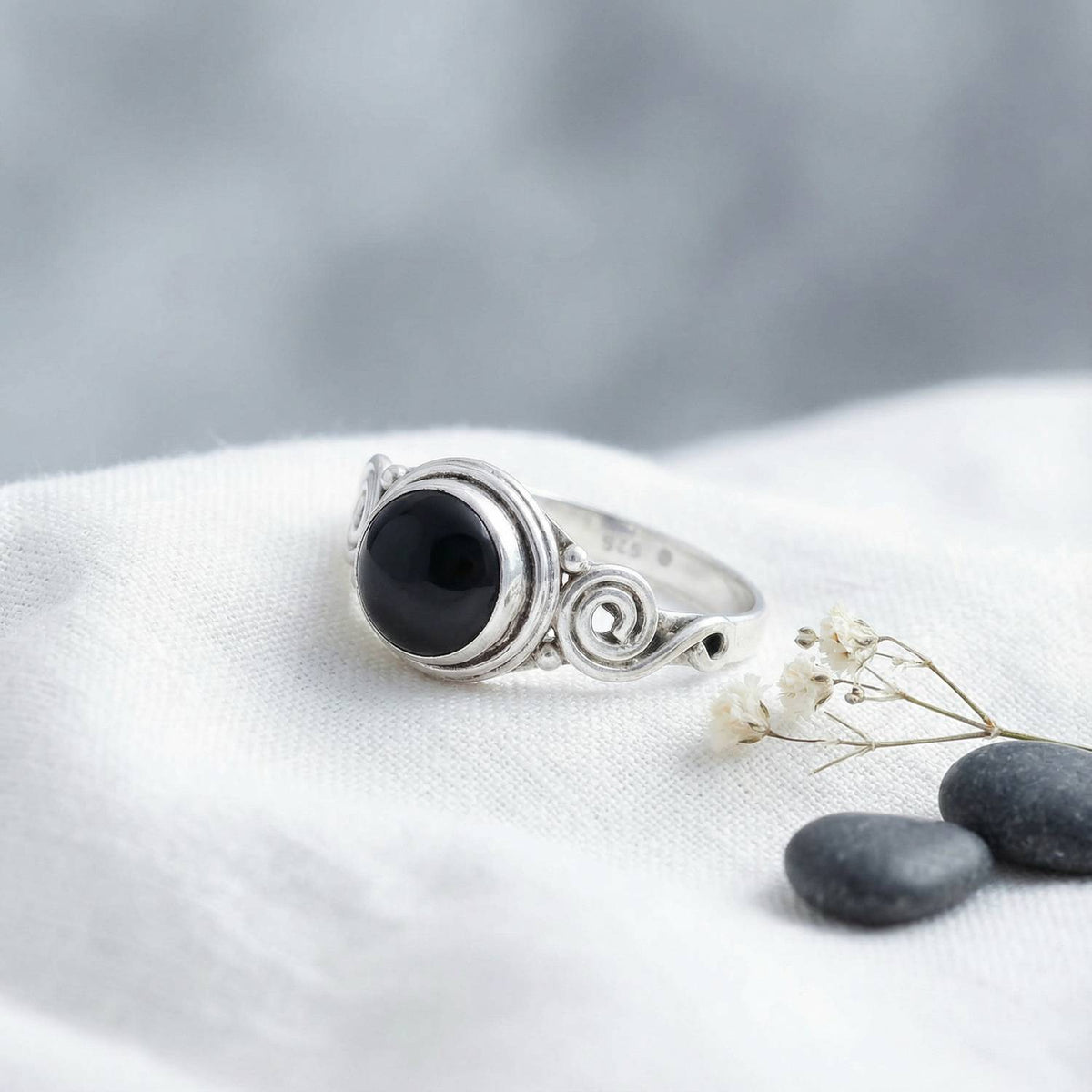 Silberring mit Onyx auf hellem Stoff