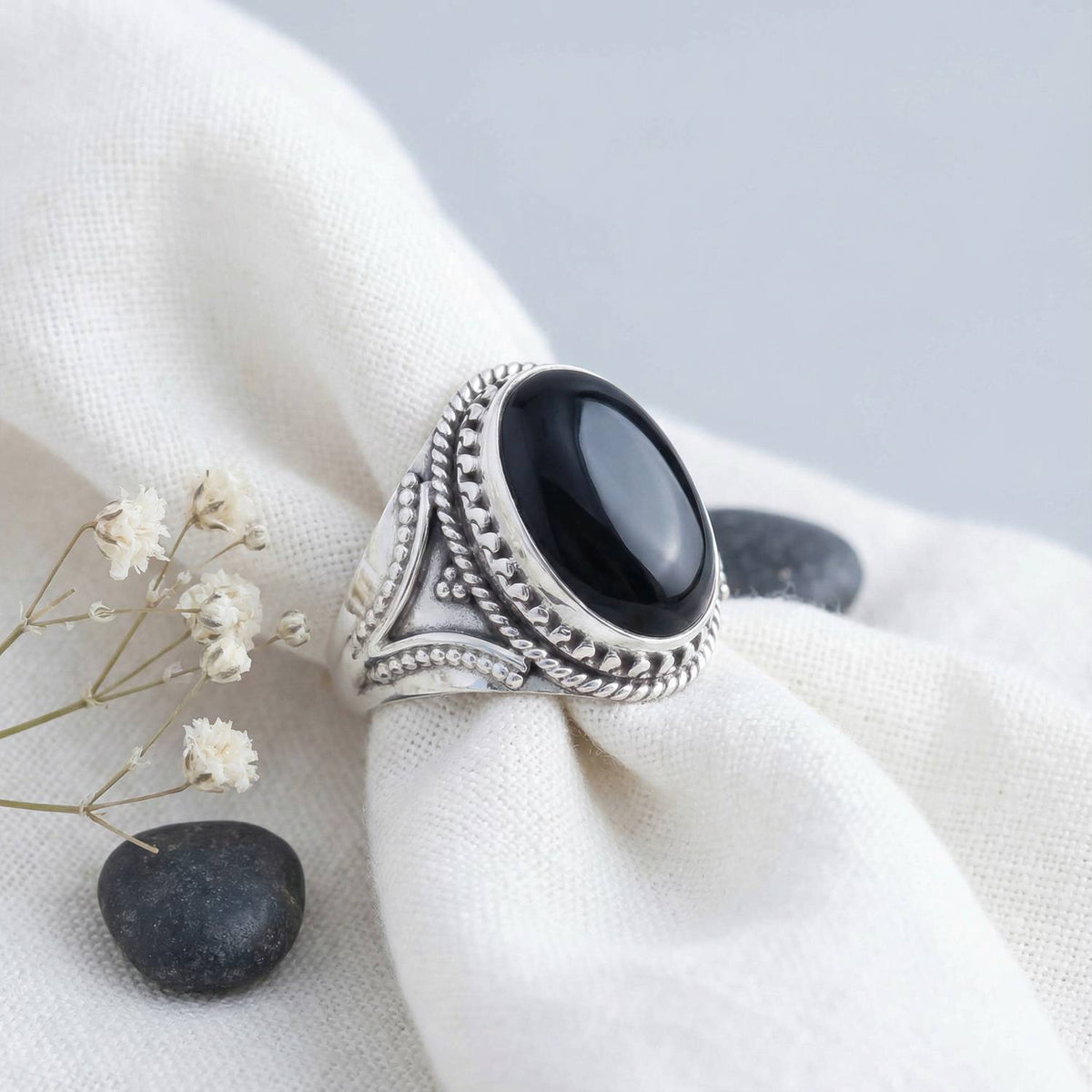 Silberring mit Onyx auf hellem Stoff