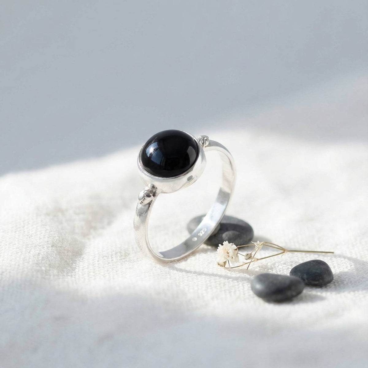Silberring mit Onyx auf hellem Stoff