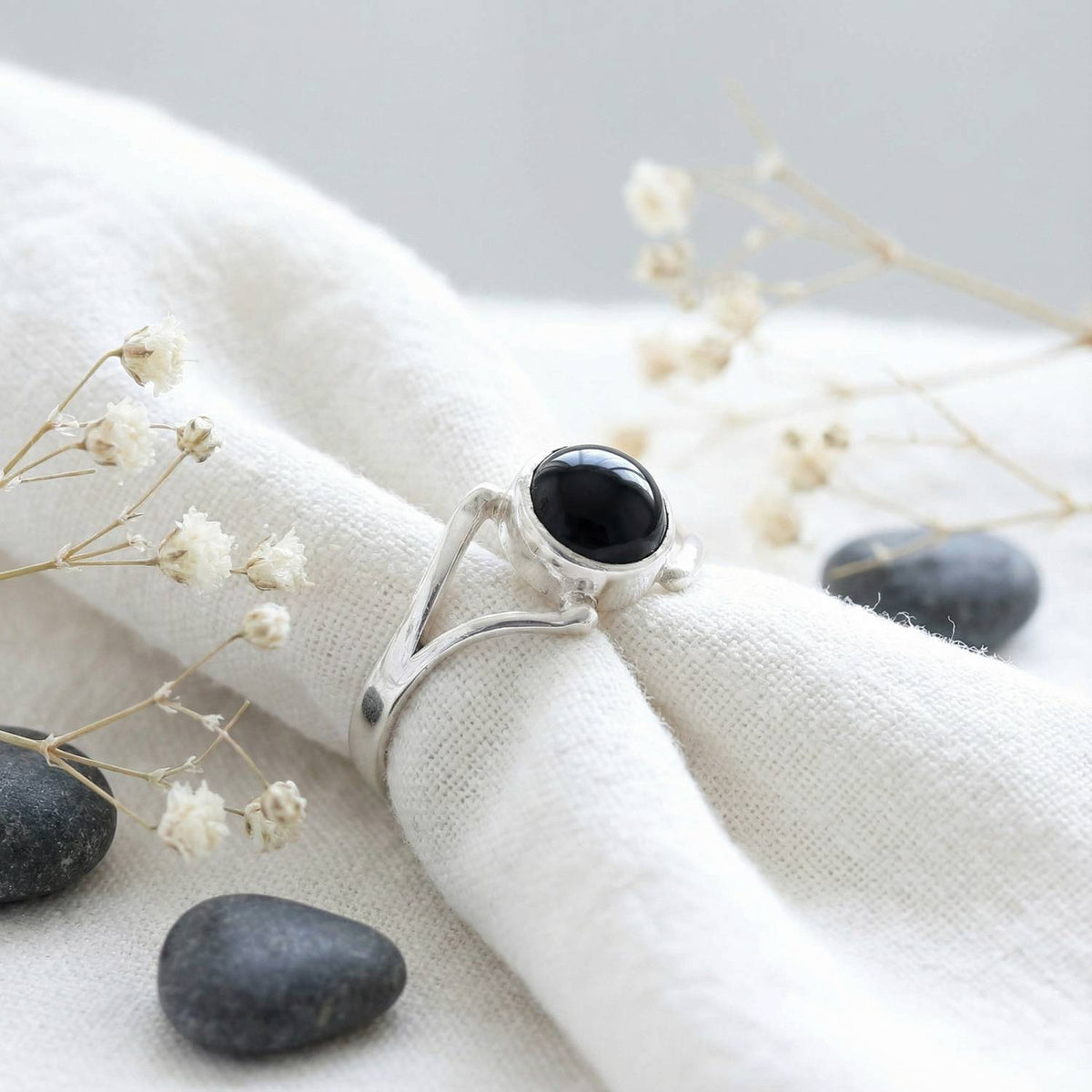 Silberring mit Onyx auf hellem Stoff