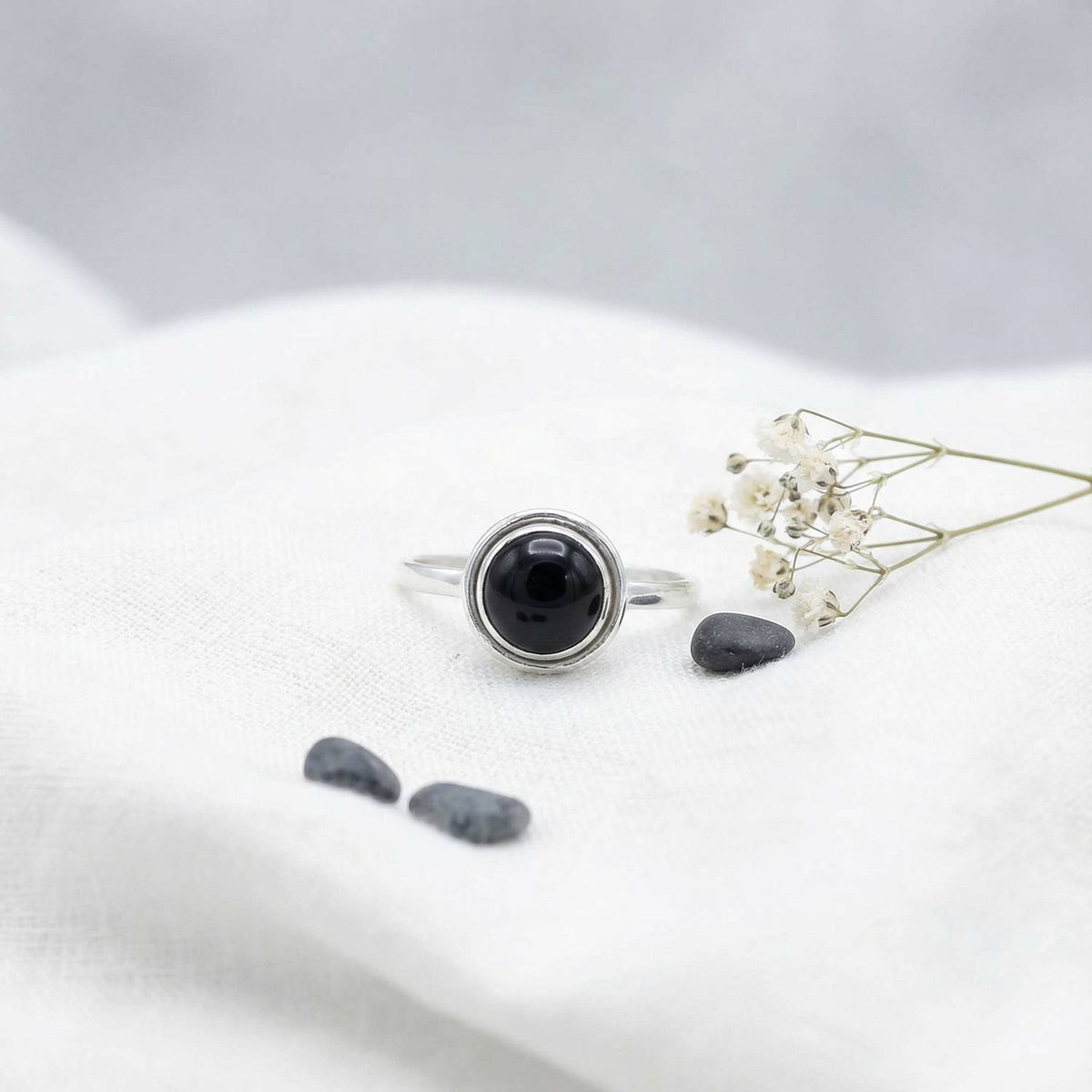 Silberring mit Onyx auf hellem Stoff