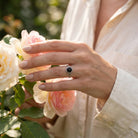 [KI] Silberring mit Onyx an der Hand zwischen Blumen