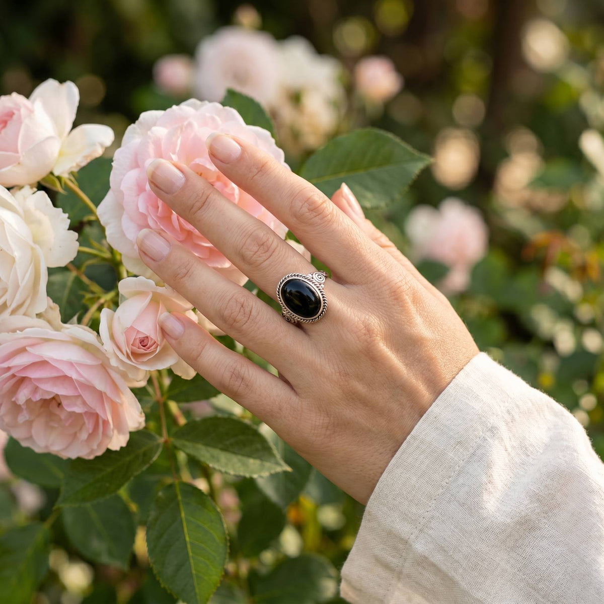 Silberring mit Onyx an der Hand zwischen Blumen