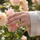 [KI] Silberring mit Onyx an der Hand zwischen Blumen
