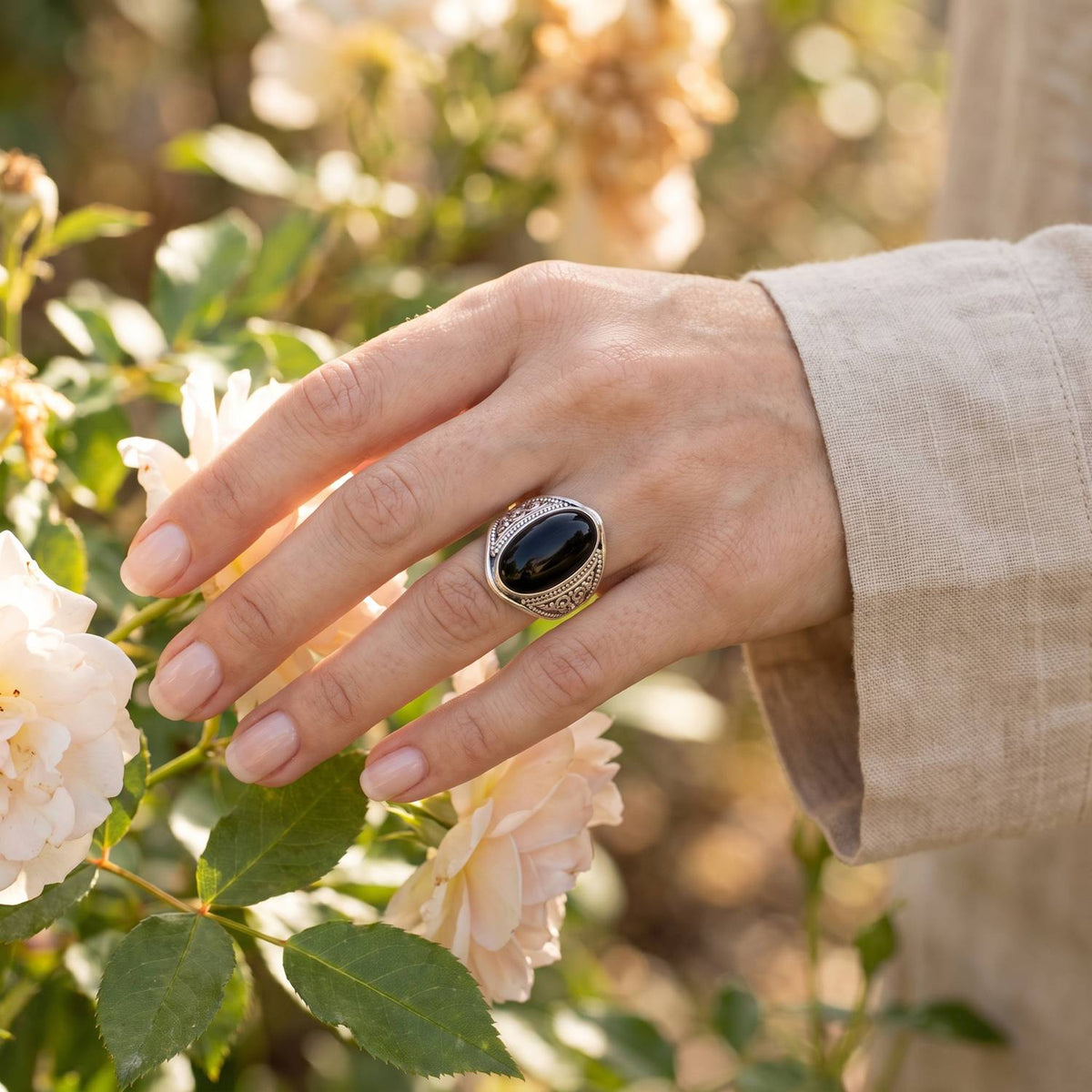 Silberring mit Onyx an der Hand zwischen Blumen