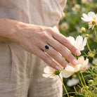 [KI] Silberring mit Onyx an der Hand zwischen Blumen