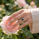 [KI] Silberring mit Onyx an der Hand zwischen Blumen