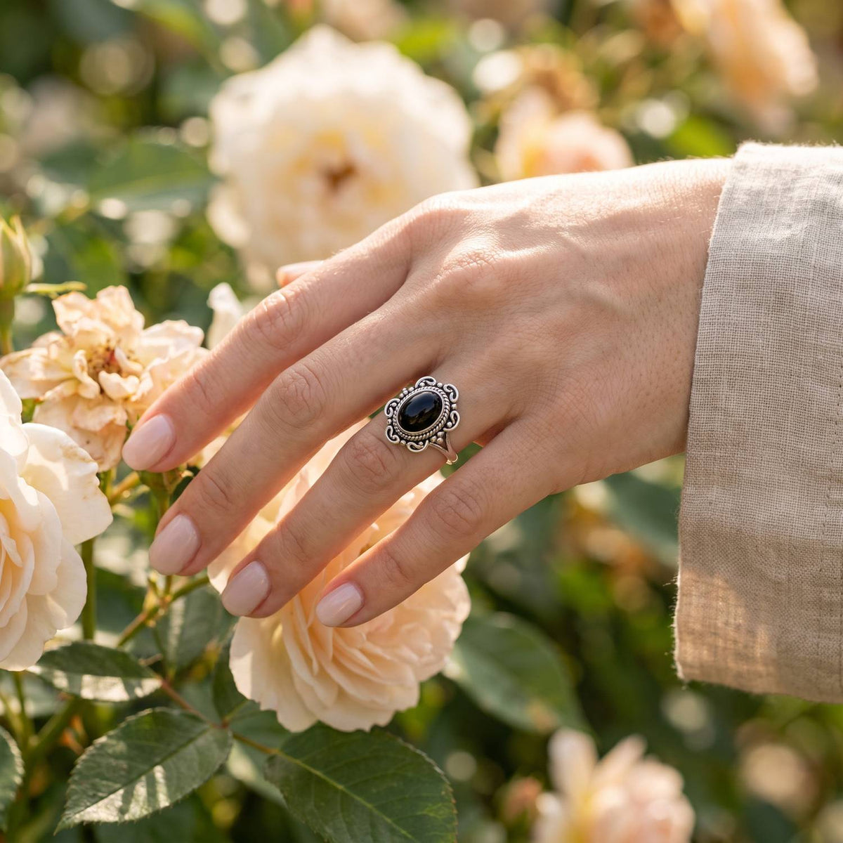 Silberring mit Onyx an der Hand zwischen Blumen