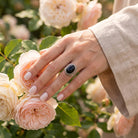 [KI] Silberring mit Onyx an der Hand zwischen Blumen