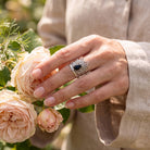 [KI] Silberring mit Onyx an der Hand zwischen Blumen