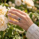 [KI] Silberring mit Onyx an der Hand zwischen Blumen