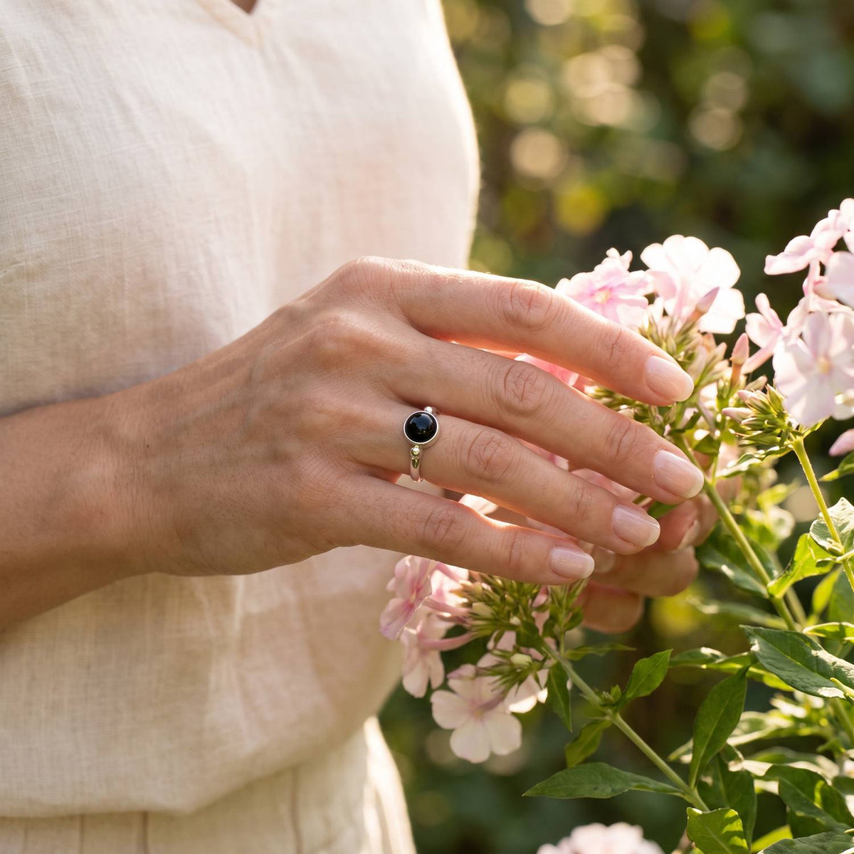Silberring mit Onyx an der Hand zwischen Blumen