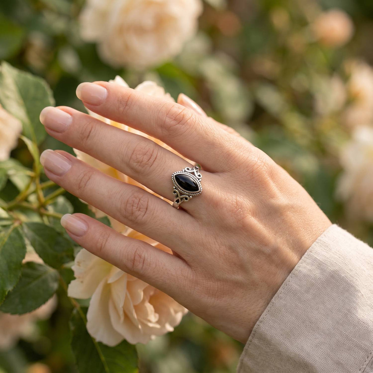 Silberring mit Onyx an der Hand zwischen Blumen