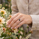 [KI] Silberring mit Onyx an der Hand zwischen Blumen