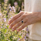 [KI] Silberring mit Onyx an der Hand zwischen Blumen