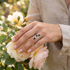 [KI] Silberring mit Onyx an der Hand zwischen Blumen