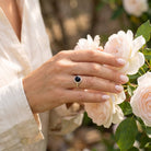 [KI] Silberring mit Onyx an der Hand zwischen Blumen