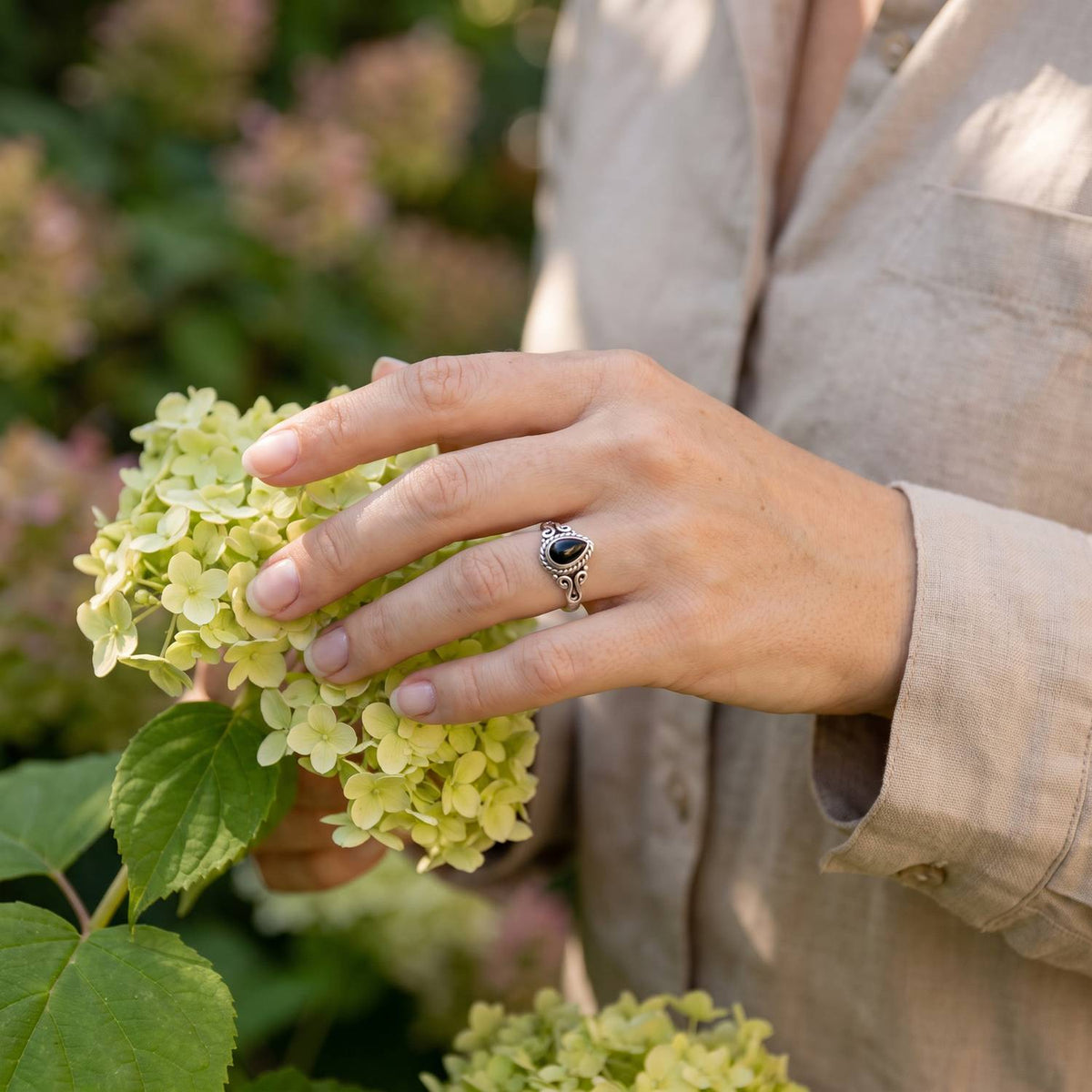 Silberring mit Onyx an der Hand zwischen Blumen