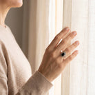 [KI] Frau trägt einen Onyxring aus Silber am Fenster