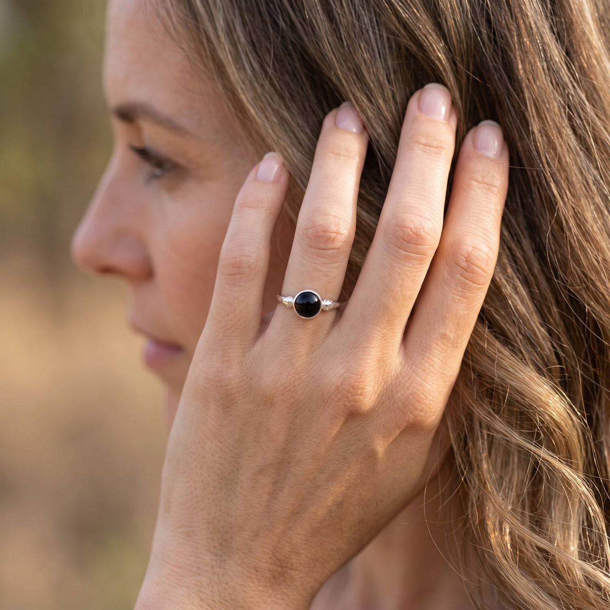Frau trägt Silberring mit Onyx an der Hand am Haar