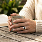 [KI] Onyxring aus Silber getragen beim Lesen mit einer Tasse