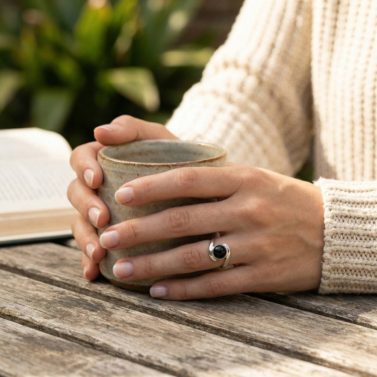 Onyxring aus Silber getragen beim Lesen mit einer Tasse