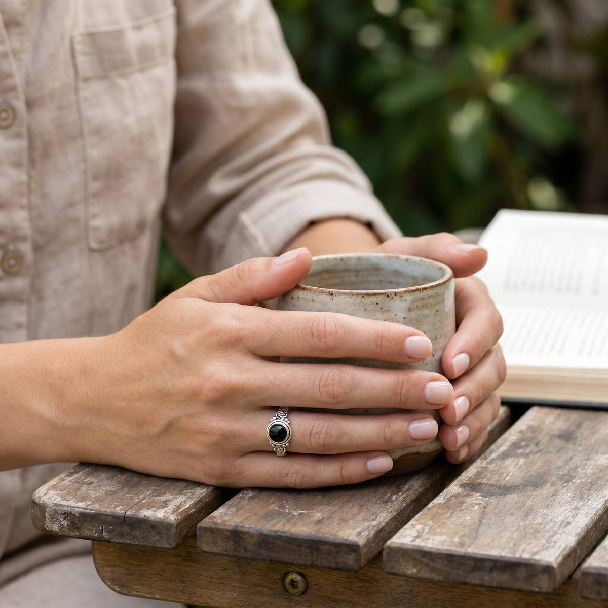 Onyxring aus Silber getragen beim Lesen mit einer Tasse