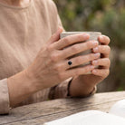 [KI] Onyxring aus Silber getragen beim Lesen mit einer Tasse