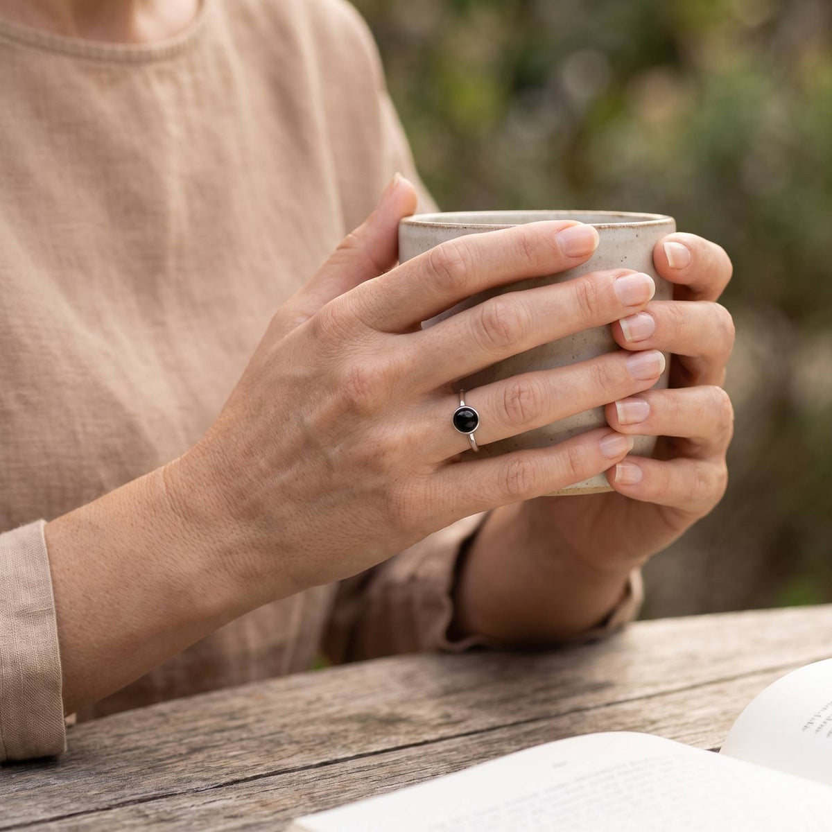 Onyxring aus Silber getragen beim Lesen mit einer Tasse