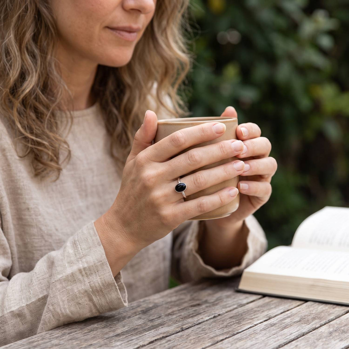 Onyxring aus Silber getragen beim Lesen mit einer Tasse