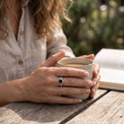 [KI] Onyxring aus Silber getragen beim Lesen mit einer Tasse