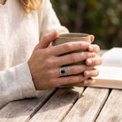 [KI] Onyxring aus Silber getragen beim Lesen mit einer Tasse