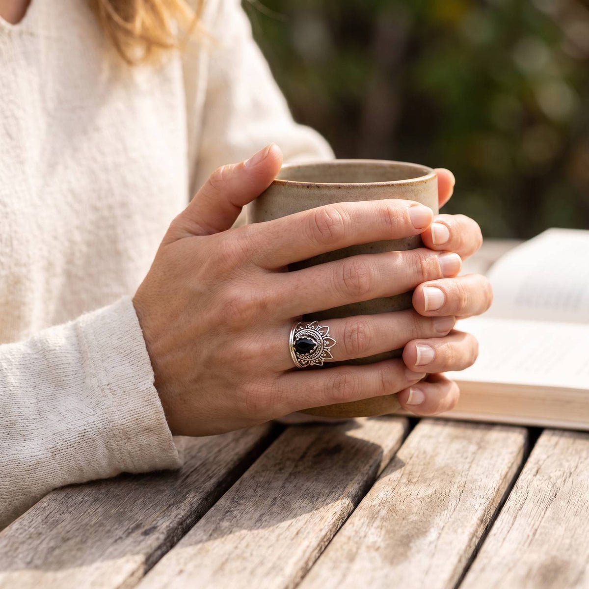 Onyxring aus Silber getragen beim Lesen mit einer Tasse
