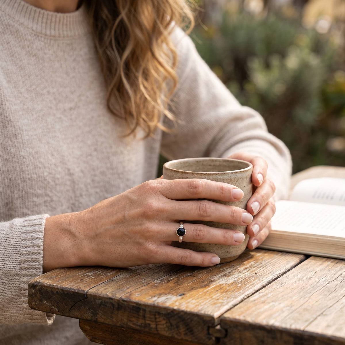 Onyxring aus Silber getragen beim Lesen mit einer Tasse