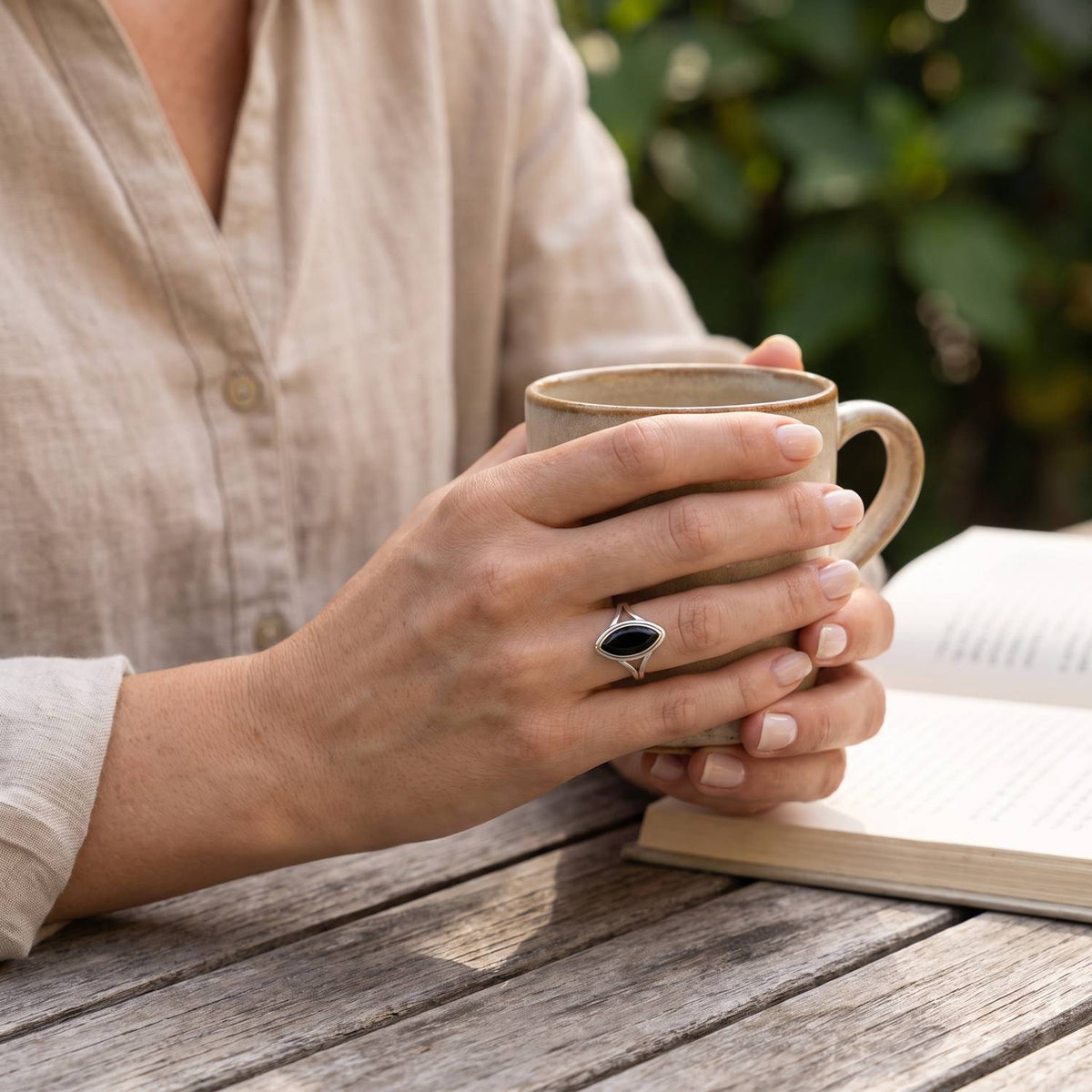 Onyxring aus Silber getragen beim Lesen mit einer Tasse