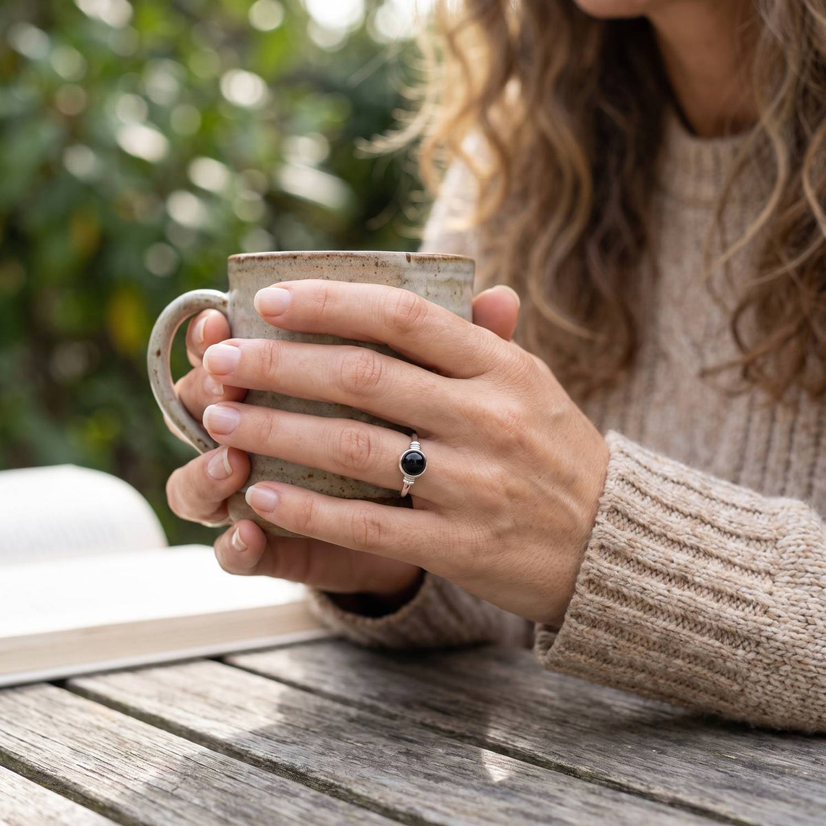 Onyxring aus Silber getragen beim Lesen mit einer Tasse