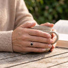[KI] Onyxring aus Silber getragen beim Lesen mit einer Tasse