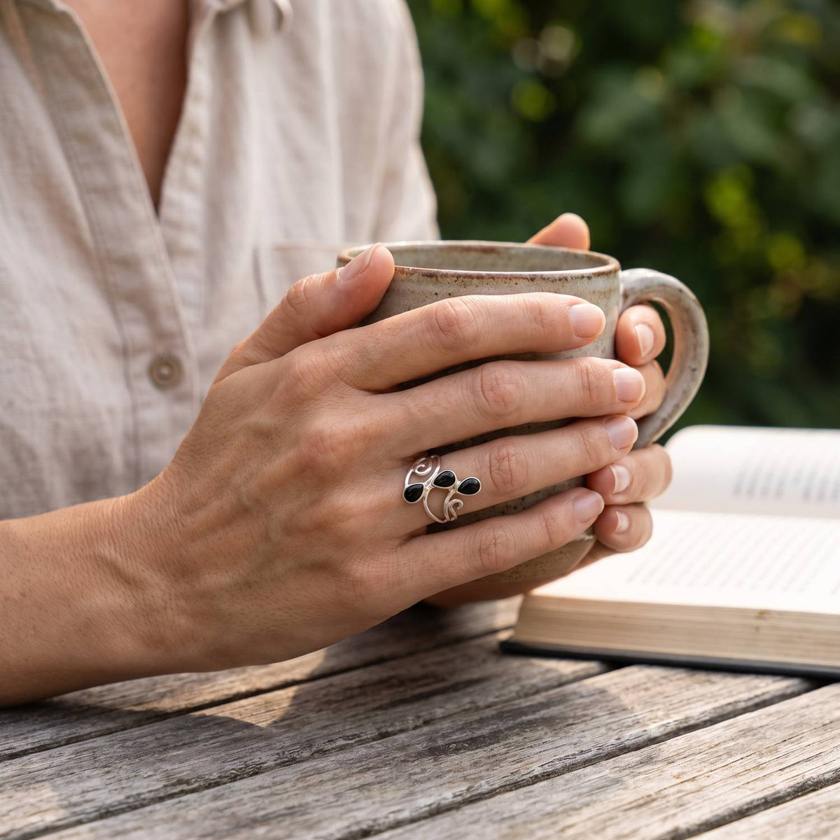Onyxring aus Silber getragen beim Lesen mit einer Tasse