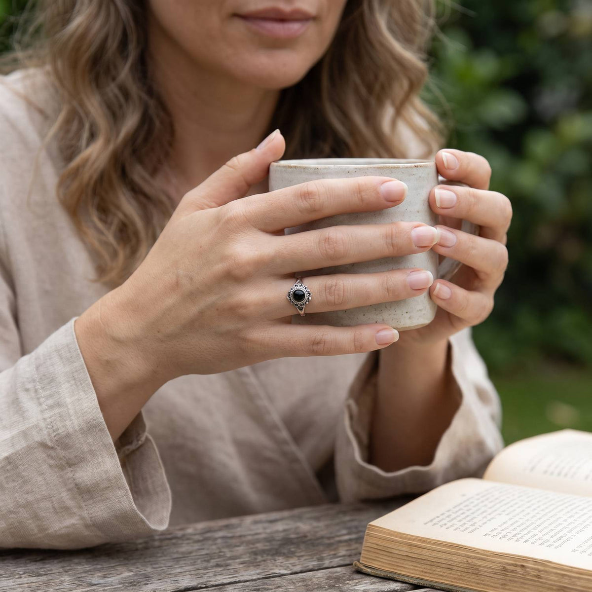 Onyxring aus Silber getragen beim Lesen mit einer Tasse