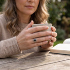 [KI] Onyxring aus Silber getragen beim Lesen mit einer Tasse