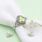 [KI] Silberring mit Peridot auf hellem Stoff