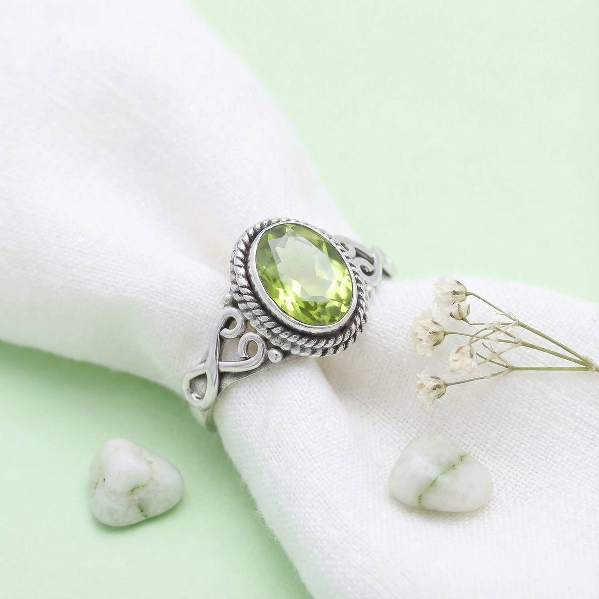 Silberring mit Peridot auf hellem Stoff