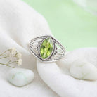 [KI] Silberring mit Peridot auf hellem Stoff