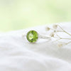 [KI] Silberring mit Peridot auf hellem Stoff