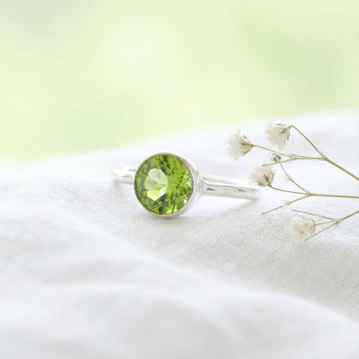 Silberring mit Peridot auf hellem Stoff