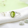 [KI] Silberring mit Peridot auf hellem Stoff
