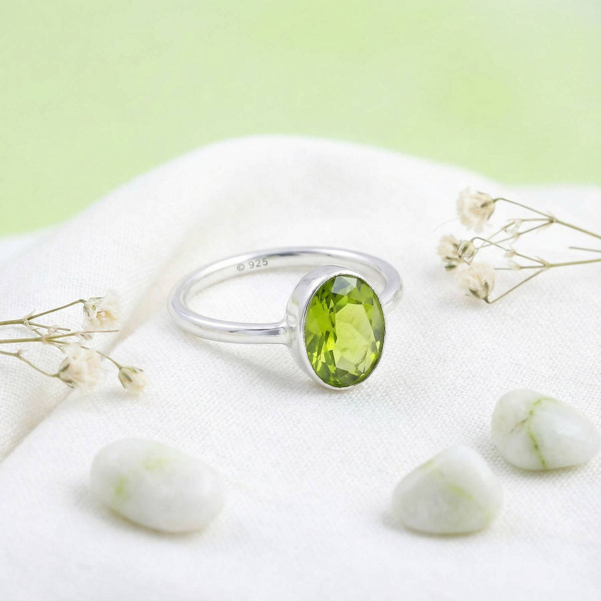 Silberring mit Peridot auf hellem Stoff